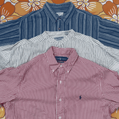 Three folded button-up shirts in red, white, and blue on a floral-patterned background