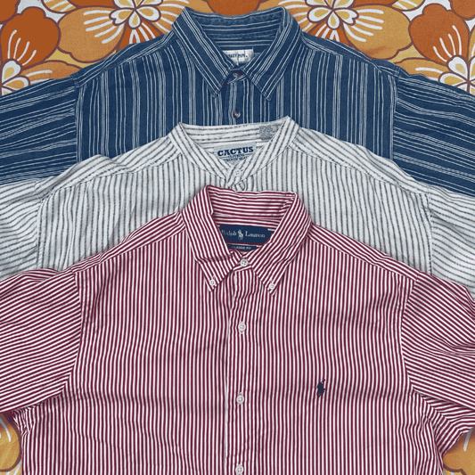 Three folded button-up shirts in red, white, and blue on a floral-patterned background